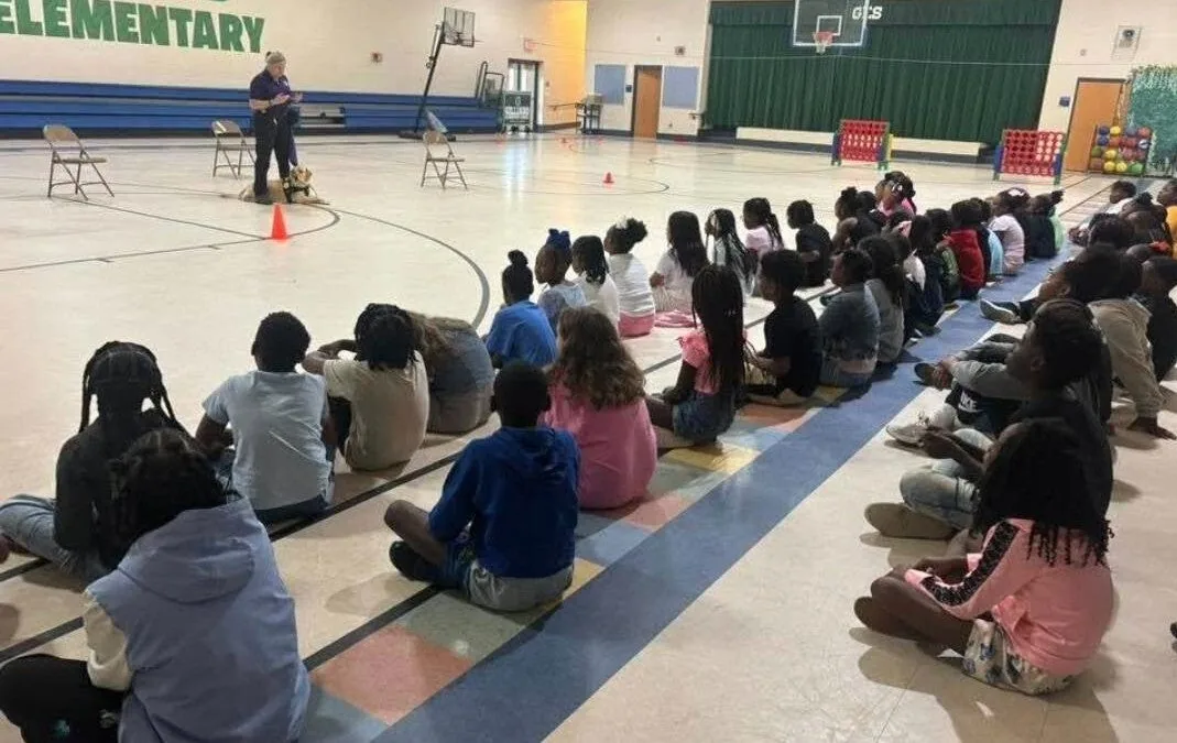 Students seated in a gym watching Estie