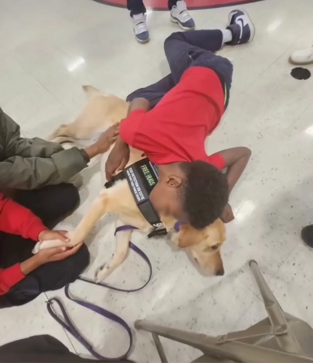 A student lying on the floor beside Estie during a school visit