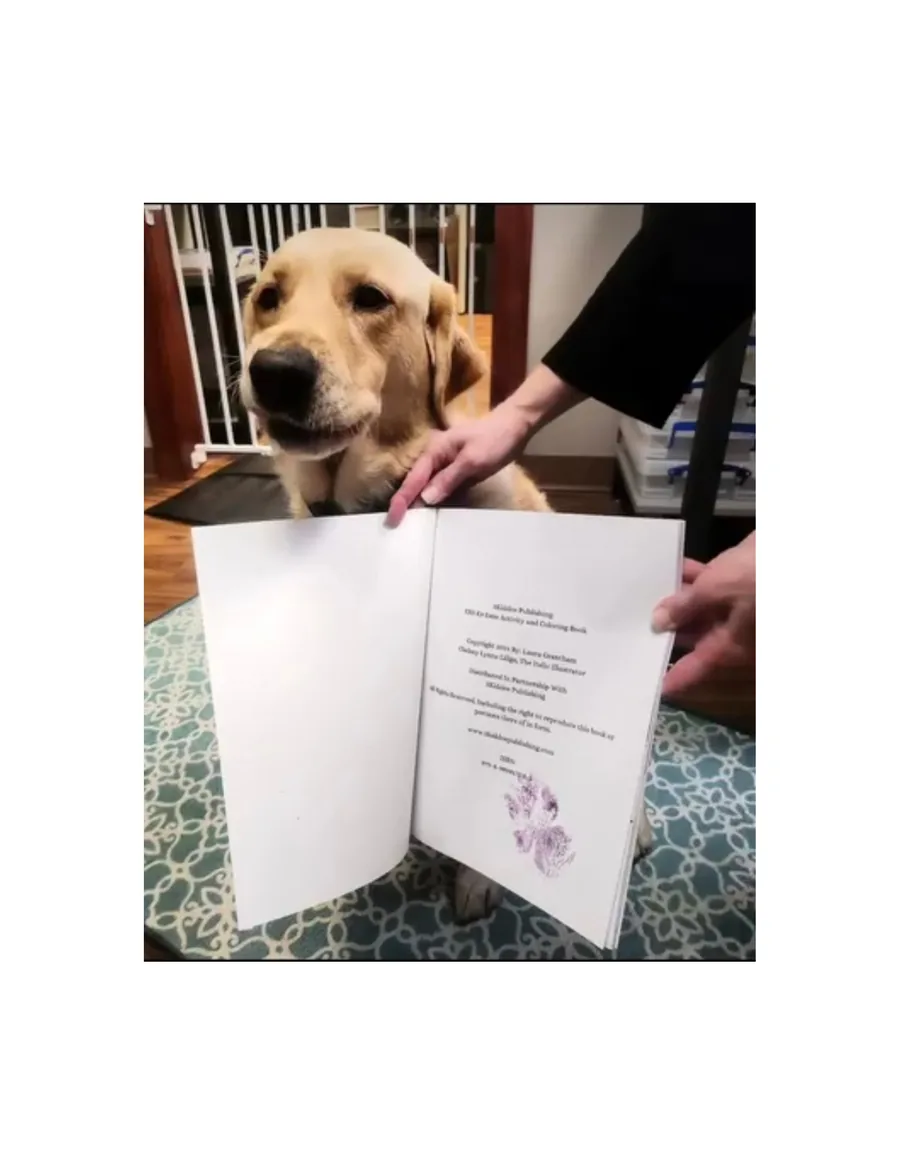 Estie signing her first book with a purple pawtograph